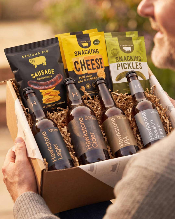 Gift box with Serious Pig sausage chips, Hawstone lager bottles, and Snacking Cheese and Pickles packaging.
